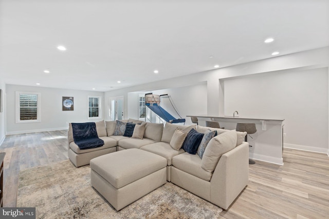 living room featuring baseboards, light wood-type flooring, and recessed lighting