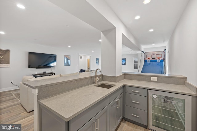 bar with recessed lighting, light wood-style flooring, a sink, beverage cooler, and baseboards