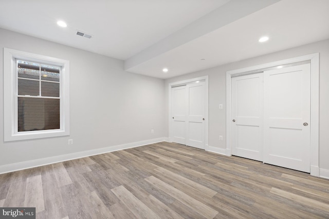 interior space with recessed lighting, baseboards, two closets, and wood finished floors