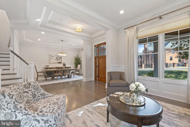 living room featuring ornamental molding, a decorative wall, stairway, and wood finished floors