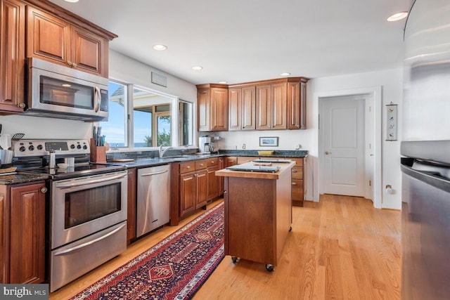 kitchen featuring recessed lighting, stainless steel appliances, a center island, light wood-style floors, and brown cabinets