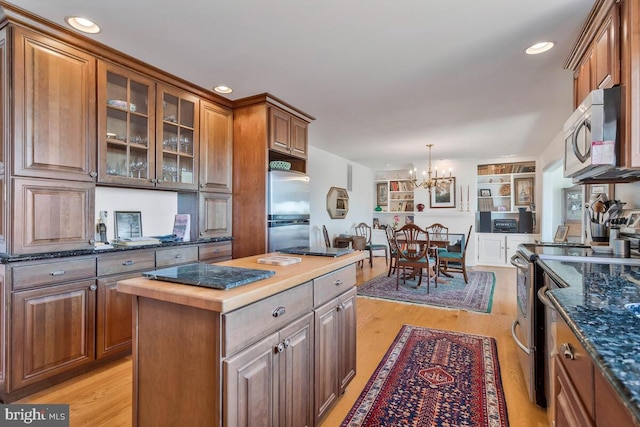 kitchen featuring stainless steel appliances, glass insert cabinets, light wood-style flooring, and brown cabinets