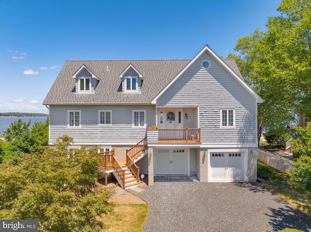 view of front facade featuring gravel driveway, an attached garage, stairs, and a shingled roof