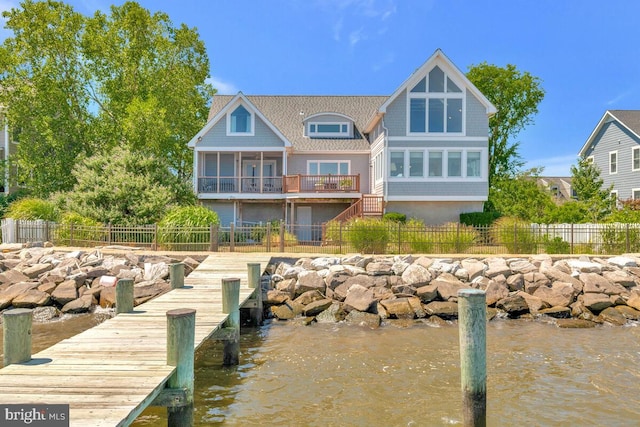 rear view of property with a sunroom, a water view, fence, and stairs