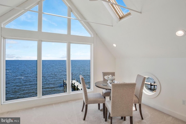 dining room featuring vaulted ceiling with skylight, baseboards, a water view, carpet, and recessed lighting