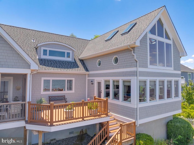 back of house with roof with shingles and a wooden deck