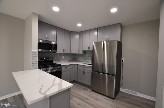 kitchen with visible vents, light stone counters, gray cabinets, appliances with stainless steel finishes, and a sink