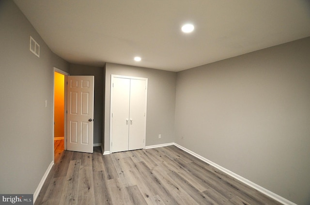 unfurnished bedroom with visible vents, baseboards, a closet, and wood finished floors