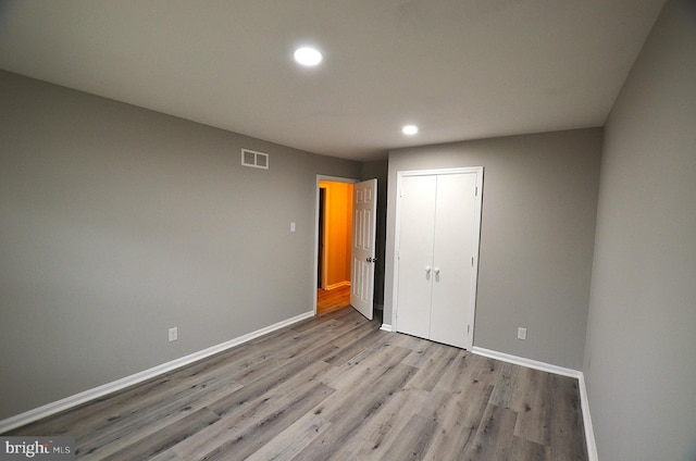 unfurnished bedroom featuring recessed lighting, wood finished floors, baseboards, and a closet