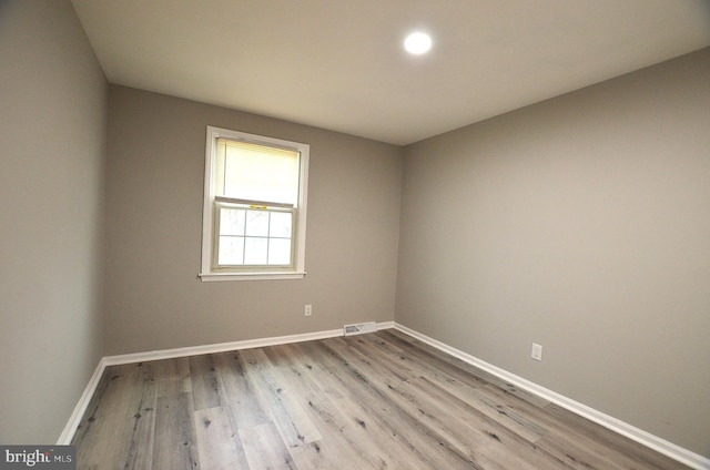 spare room featuring visible vents, baseboards, and wood finished floors