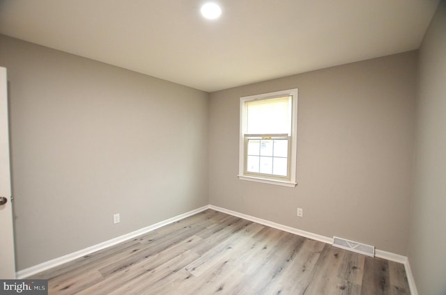 unfurnished room with visible vents, light wood-type flooring, and baseboards