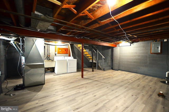 unfinished basement with electric panel, a sink, wood finished floors, stairs, and washing machine and clothes dryer