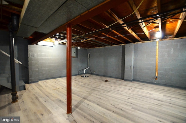 unfinished basement featuring electric panel and wood finished floors