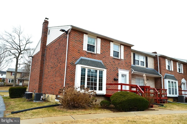 multi unit property featuring brick siding, central air condition unit, and a chimney