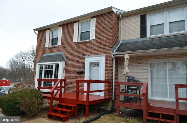 rear view of property with a wooden deck, brick siding, and a shingled roof