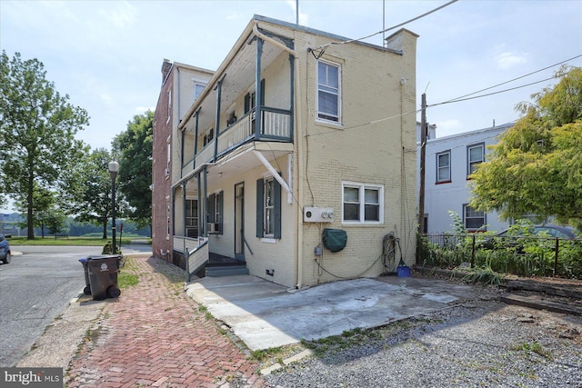 exterior space featuring brick siding, fence, a balcony, and a patio