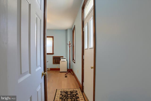 hallway featuring light wood finished floors and baseboards