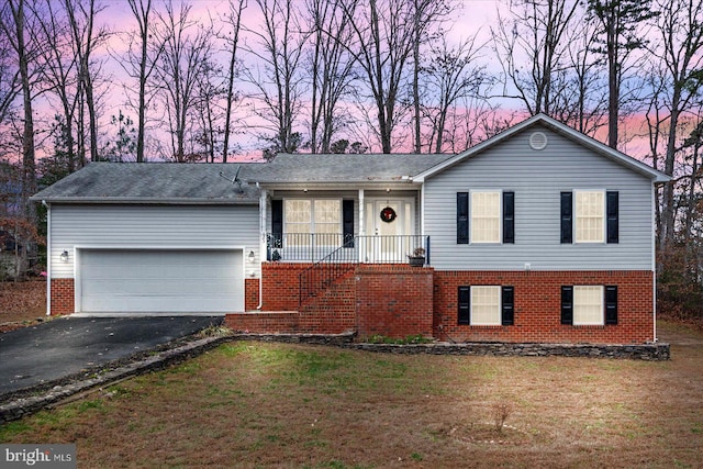 view of front of house with brick siding, covered porch, driveway, and a front yard