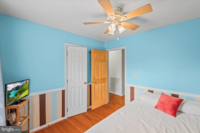 bedroom with visible vents, baseboards, a ceiling fan, and wood finished floors