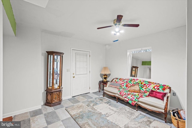 living area with a ceiling fan and baseboards