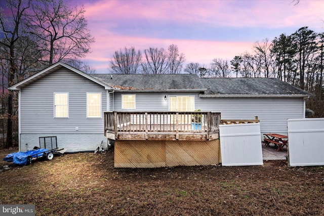 back of property featuring a shingled roof and a deck