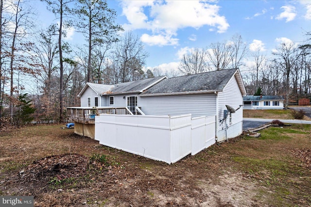 rear view of property featuring a wooden deck and roof with shingles