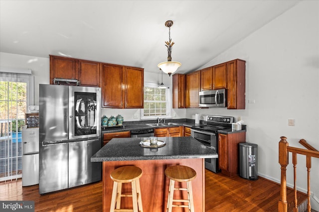 kitchen with dark countertops, a kitchen island, dark wood-style floors, stainless steel appliances, and a sink