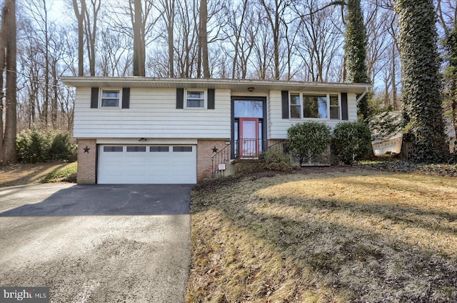 split foyer home with an attached garage, brick siding, and driveway