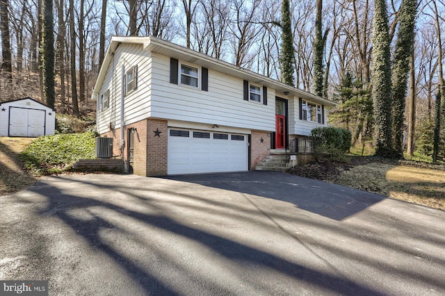 bi-level home with driveway, cooling unit, a storage shed, an outdoor structure, and brick siding