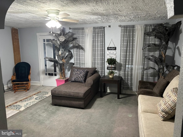 living area featuring a baseboard radiator, ceiling fan, a textured ceiling, wood finished floors, and baseboards