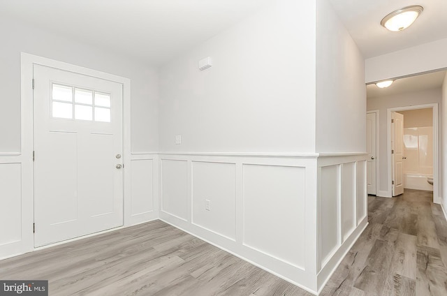 entrance foyer with a wainscoted wall and light wood-style floors