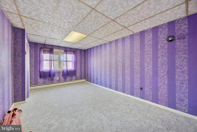 empty room with carpet floors, wallpapered walls, baseboard heating, and a drop ceiling