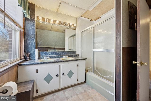 full bathroom featuring combined bath / shower with glass door, a sink, and double vanity