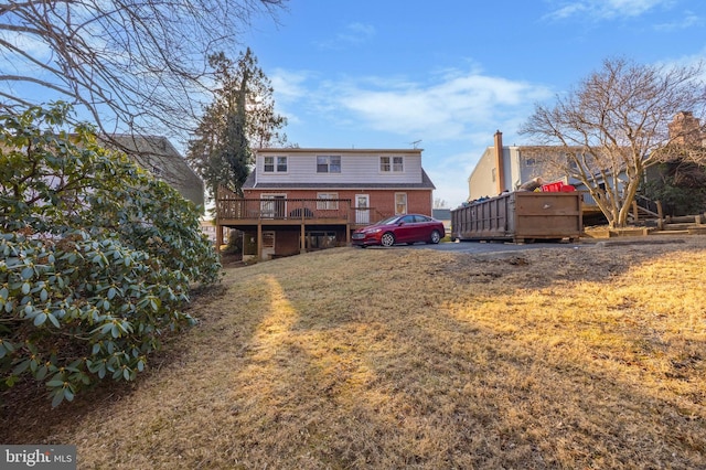 rear view of property featuring a deck, brick siding, and a lawn