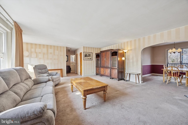 living area featuring light carpet, wallpapered walls, baseboards, and arched walkways