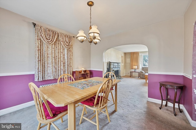 carpeted dining area featuring an inviting chandelier, baseboards, and arched walkways