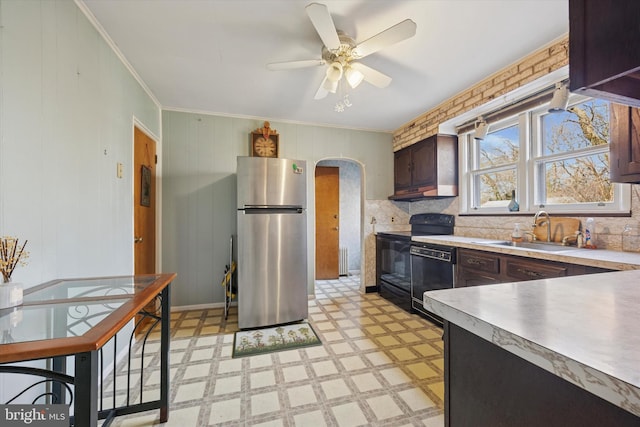 kitchen with black dishwasher, arched walkways, freestanding refrigerator, light floors, and a sink