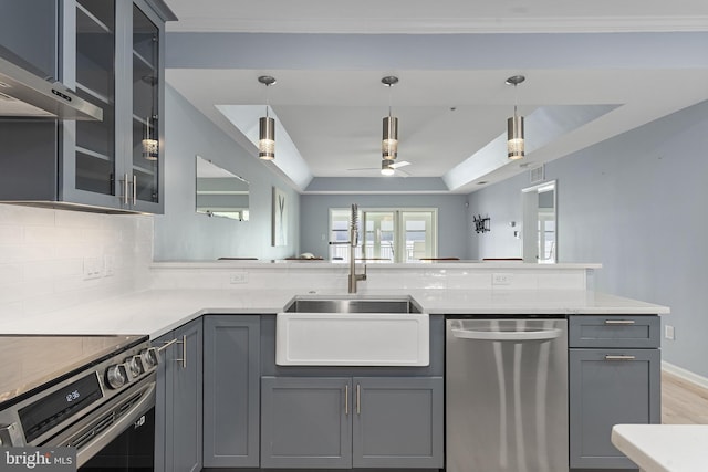 kitchen featuring gray cabinets, a sink, appliances with stainless steel finishes, decorative backsplash, and hanging light fixtures