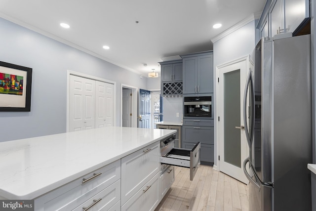 kitchen with ornamental molding, recessed lighting, appliances with stainless steel finishes, light wood finished floors, and light stone countertops