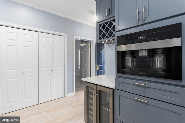 kitchen with oven, beverage cooler, crown molding, and light wood finished floors