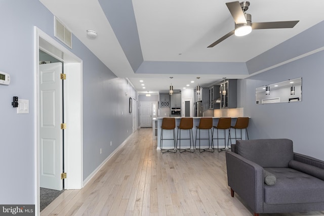 interior space with visible vents, light wood finished floors, a peninsula, appliances with stainless steel finishes, and a kitchen bar