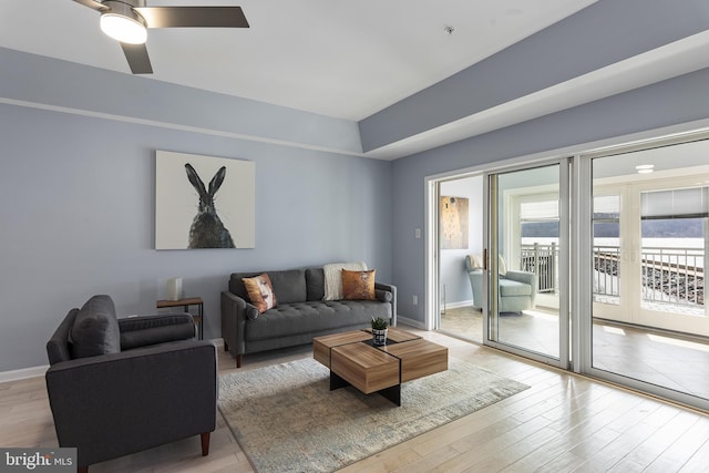 living area with baseboards, light wood-style floors, and a ceiling fan