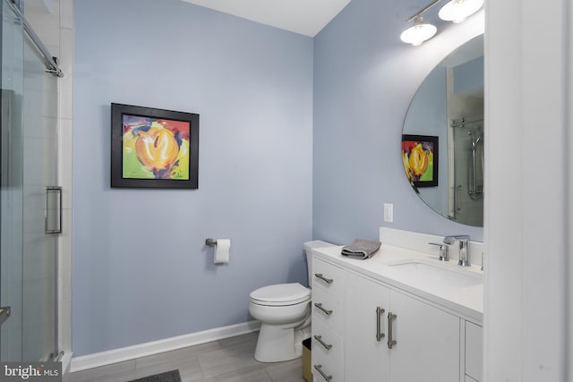 bathroom with a tile shower, toilet, vanity, and baseboards