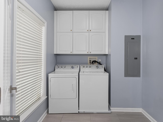 clothes washing area featuring electric panel, baseboards, cabinet space, and independent washer and dryer