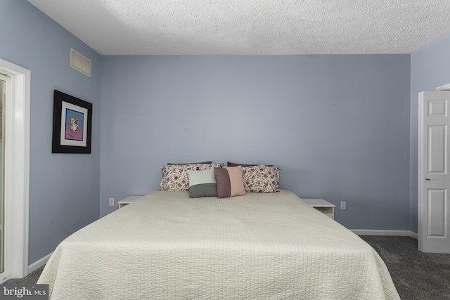 bedroom with baseboards, visible vents, dark carpet, and a textured ceiling