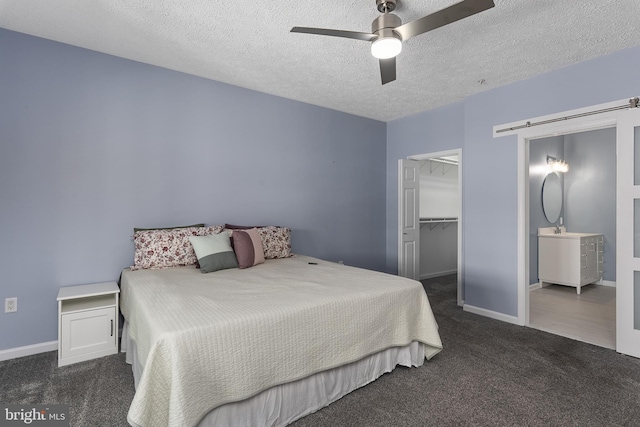 carpeted bedroom with a barn door, baseboards, a textured ceiling, and a spacious closet