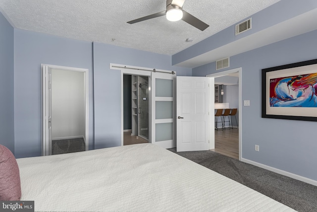 bedroom with visible vents, a textured ceiling, carpet, and a barn door