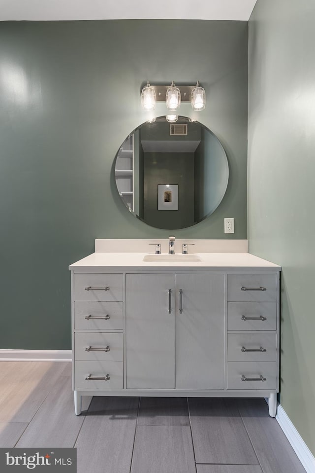 bathroom featuring visible vents, baseboards, wood finished floors, and vanity