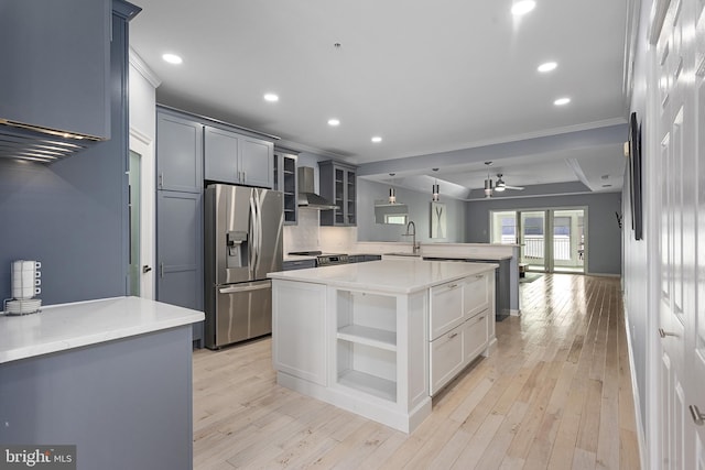 kitchen featuring a peninsula, open shelves, stainless steel appliances, light wood-style floors, and wall chimney range hood