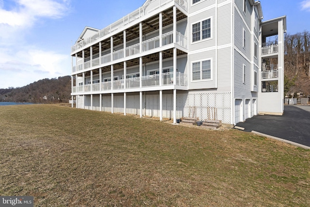 rear view of house featuring aphalt driveway, an attached garage, and a yard